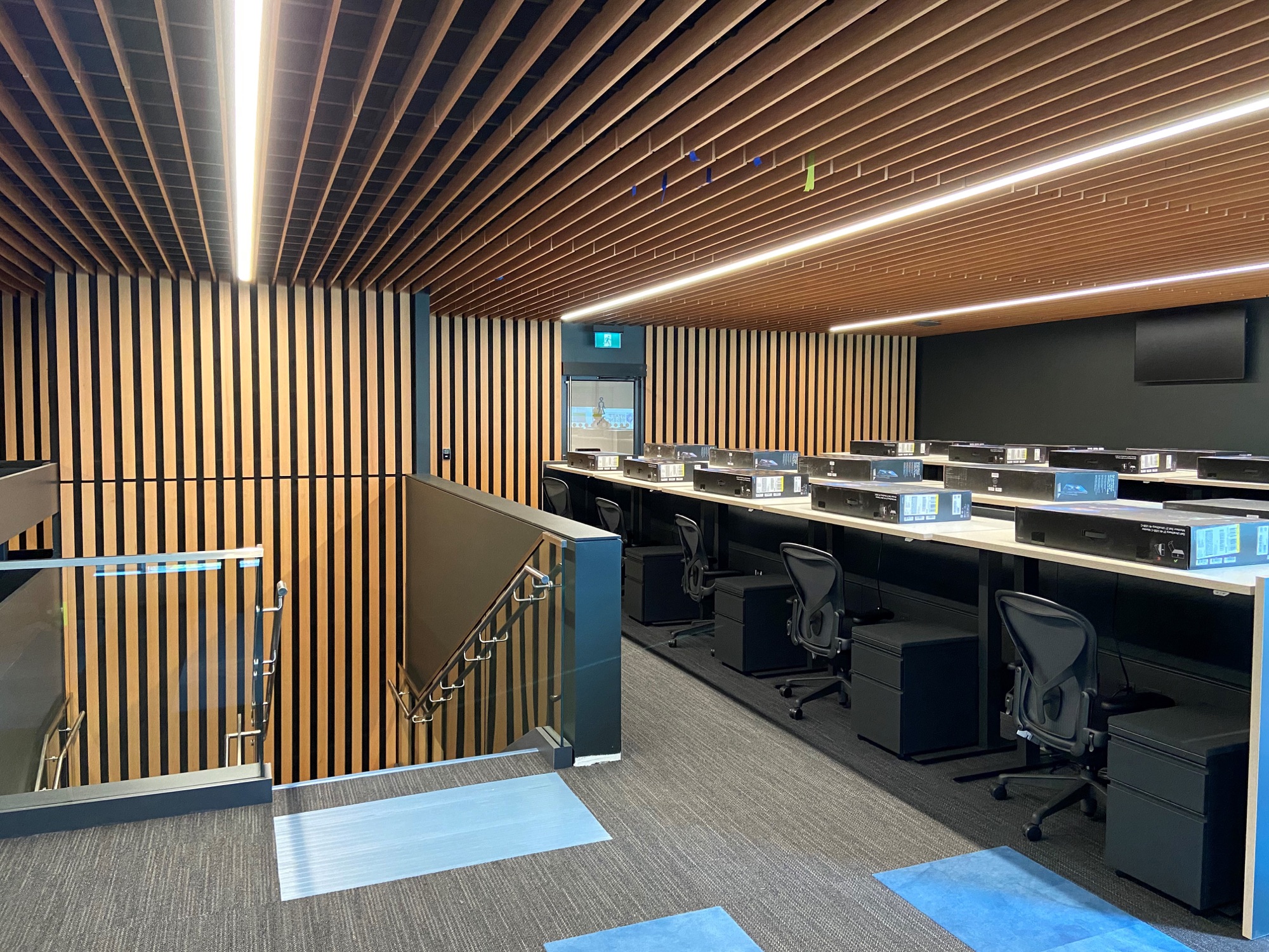Slatted walls and ceiling with linear lighting in a tiered workspace at Slack
